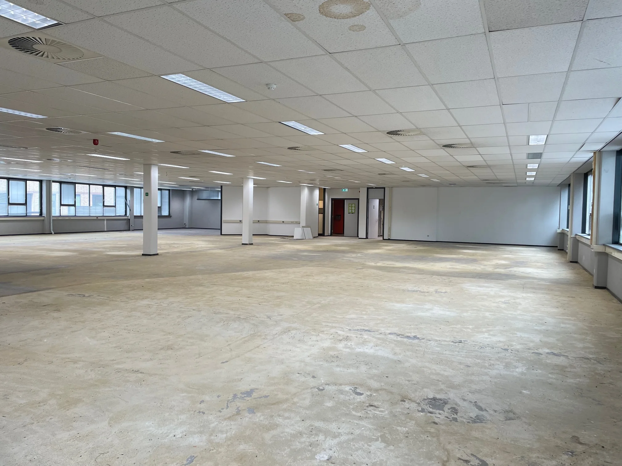 Leeg kantoorpand aan de Rivium 4e Straat met systeemplafond en grote ramen.